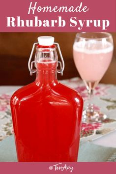 homemade rhubarb syrup in a glass bottle on a table next to a pink drink