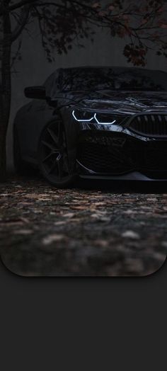 a car parked in front of a tree with its headlights turned on at night time