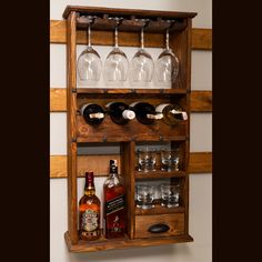 a wooden shelf with wine glasses and bottles on it's side, holding several liquor glasses