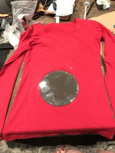 a red shirt is sitting on the table next to some scissors and other crafting supplies