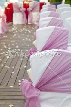 rows of white and pink chairs with bows on them