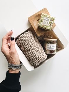 a woman's hands holding a box with some food in it on top of a table