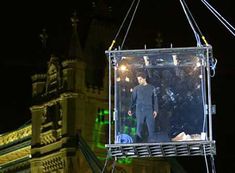 a man is standing in the middle of a box suspended from a building at night