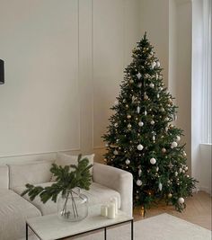 a living room with a christmas tree in the corner next to a couch and coffee table