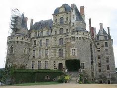 an old castle with a clock on the front and stairs leading up to it's entrance