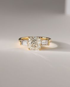 a yellow gold ring with an oval cut diamond and baguets on the side