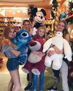 some people are posing with stuffed animals and mickey mouse in a store together for a photo