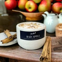 a white candle sitting on top of a table next to some cinnamon sticks and apples