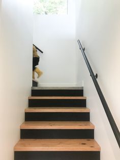 the stairs are made of wood and have black handrails, along with a white wall