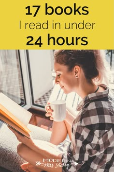 a woman sitting on a couch reading a book and drinking coffee in front of a window