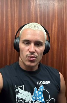 a man with white hair wearing headphones in front of a wooden paneled wall