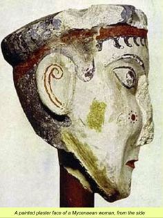 the head of a statue is on a wooden pole with a white wall behind it