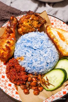 a plate with rice, cucumbers, and other food items on top of it