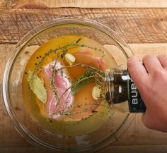 a person is pouring sauce into a bowl with meat and vegetables in it on a wooden table