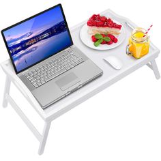 an open laptop computer sitting on top of a white table next to a plate of food