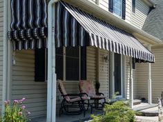 an awning on the side of a house in front of a table and chairs