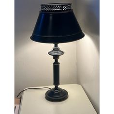 a lamp that is sitting on top of a table with a black shade over it