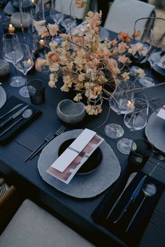 the table is set with black and white place settings, silverware, and flowers