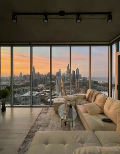 a living room filled with furniture and large windows overlooking the cityscape at sunset