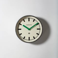 a white clock with green hands on a wall