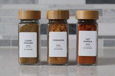 three jars filled with spices sitting on top of a counter