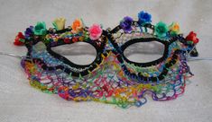 Hand embroidered needlelace mask with cotton and metallic thread, sequins, glass beads, and wire.  Pastel colored flowers molded from polymer fimo dough across the top edge.  Rainbow colored needlelace veil covers the nose and upper lip.  Silver tone elastic ties included. Floral Mask, Jester Hat, Raffia Hat, Costume Masks, Flower Molding, Custom Made Shirts, Colored Flowers, Upper Lip, Costume Mask