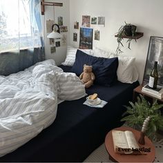 there is a stuffed bear sitting on the bed in this room with blue and white sheets