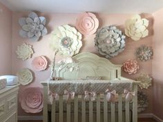 a baby's room decorated in pink and white with paper flowers on the wall