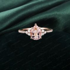 a ring with an oval cut pink morganite surrounded by small diamonds on a green velvet background