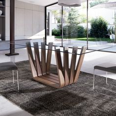 a glass dining table with an unusual design in the center and chairs around it on carpeted flooring