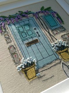 an embroidered picture of a blue door with flowers in the potted planter on the outside