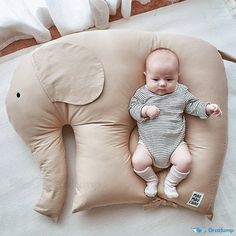 a baby laying on an elephant shaped pillow