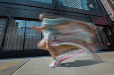 a blurry photo of a man running on the sidewalk in front of a building