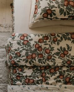 a bed with two pillows on top of it and an apple print comforter next to each other