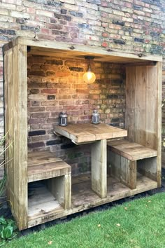 a wooden table and benches in front of a brick wall with an outdoor light on it