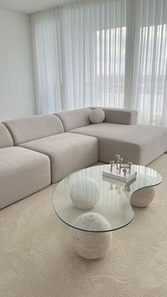 a living room filled with furniture and a large window covered in white sheer curtaines