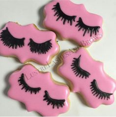 three decorated cookies with fake eyelashes on top of each cookie, one is pink and the other is black