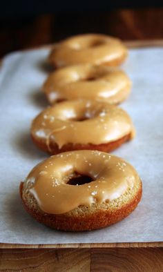 three glazed doughnuts lined up on a paper towel