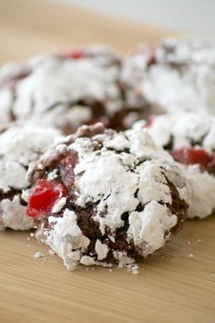 chocolate cherry cookies with powdered sugar are on a wooden surface, ready to be eaten