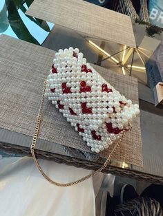 a handbag made out of pearls and red hearts on a table with other items