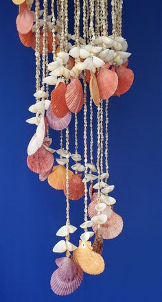 seashells and pearls hang from the ceiling in front of a blue background,