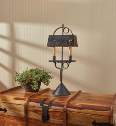 an old trunk is sitting on the floor next to a lamp and potted plant