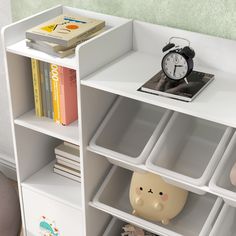 a white book shelf with books and an alarm clock sitting on it's side