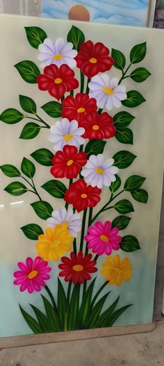 a painting with flowers painted on it in the process of being made into a wall hanging