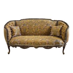 an old fashioned couch with floral fabric on the back and gold trimming, sitting against a white background