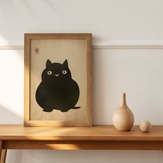 a black cat sitting on top of a wooden table next to a vase and painting