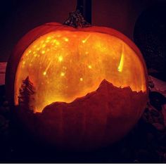 a carved pumpkin sitting on top of a rock filled with leaves and lights in the dark