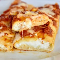 two pieces of pizza sitting on top of a white plate covered in sauce and cheese