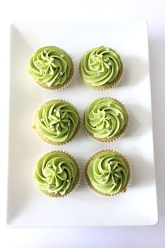 six cupcakes with green frosting on a white square plate, ready to be eaten