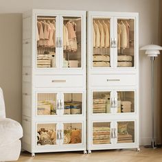 a white chair sitting next to a tall cabinet filled with clothes